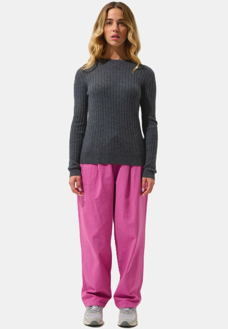 Suéter gris con canalé combinado con pantalones rosas holgados y zapatillas grises. El suéter tiene un diseño ajustado, y los pantalones tienen un acabado texturizado.