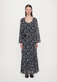 Abito lungo nero a fiori con scollatura a barco, maniche lunghe in tessuto trasparente e fondo a strati. Presenta motivi floreali blu chiaro e bianchi e una cintura nera.
