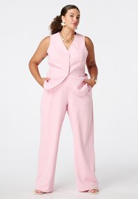 Roze op maat gemaakte gilet en brede broek gemaakt van zacht materiaal. Voorzien van knoopsluiting en zijzakken, wat een slanke silhouet creëert.