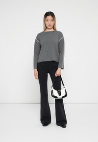 Gray cropped sweater with contrast stitching, paired with black flared trousers. Accessory includes a small black and white handbag.