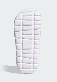 Biała podeszwa trampka z teksturowanym wzorem antypoślizgowym, z centralnym logo i zaokrąglonym brzegiem. Jasnoróżowe akcenty na pięcie.