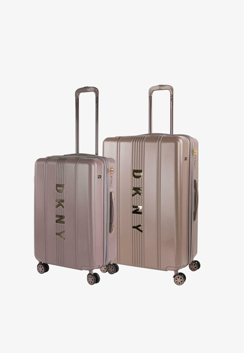 Dos maletas rígidas de DKNY en un color rosa dorado claro, con textura acanalada, acabado brillante y ruedas negras, exhiben un logotipo prominente.