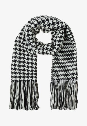 Zwart-wit geweven sjaal met ruitmotief, franjes aan de uiteinden en een dikke gebreide textuur, losjes geknoopt in een lus.