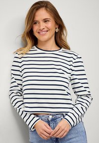 Gestreept T-shirt met lange mouwen in marineblauw en wit, een ronde halslijn en een cropped ontwerp, gecombineerd met high-waisted denim shorts.