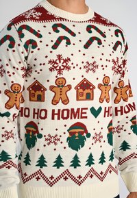 Breipully in crème met rode en groene patronen, met peperkoekmannetjes, huizen, zuurstokken, kerstbomen en de tekst "HO HO HOME."