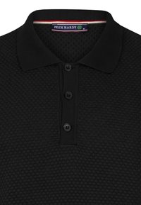 Zwarte polo shirt van een textuurstof, met een drieknops sluiting en een kraag met een rood-witte streepdetail. Merkenlabel zichtbaar.