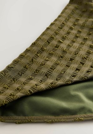 Grüner Stoff mit einem strukturierten, gewebten Schachbrettmuster auf der oberen Schicht und einer glatten, einfarbigen grünen Unterseite. Kante mit Naht verarbeitet.