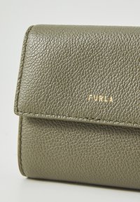 Green textured leather wallet with a fold-over flap, featuring a gold "FURLA" logo on the front and subtle stitching details.