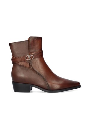 Bota de cuero marrón hasta el tobillo con un tacón bajo negro, punta en pico y una correa decorativa con hebilla plateada en el lateral.