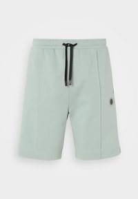 Shorts vert clair en tissu doux, dotés d'une taille élastique avec un cordon de serrage noir, de poches latérales et d'un petit logo.