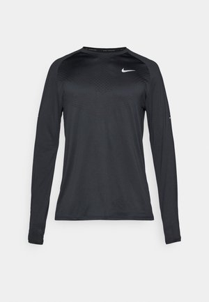 Zwart sportshirt met lange mouwen, gemaakt van een gladde, elastische stof. Heeft een subtiele textuur en een klein wit logo op de borst.