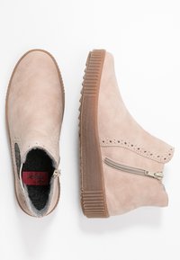 Botines de ante beige con suela de goma texturizada, cremallera lateral y acentos de diseño perforado, además de un forro interior suave.
