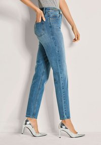 Lichtblauwe denim jeans met een strakke pasvorm, rechte benen en vijf pockets. Gecombineerd met zilveren hoge hakken.