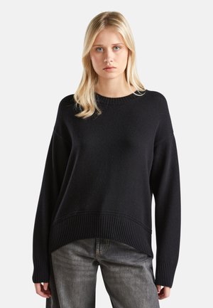Pull en tricot noir avec un ourlet et des poignets côtelés, offrant une coupe décontractée. Le tissu a une finition texturée et un col rond classique.