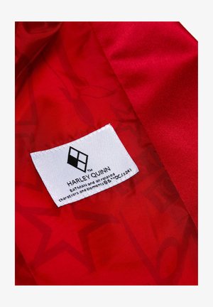 Red satin fabric interior featuring a white label with black text and a diamond logo, indicating "HARLEY QUINN" and related trademarks.