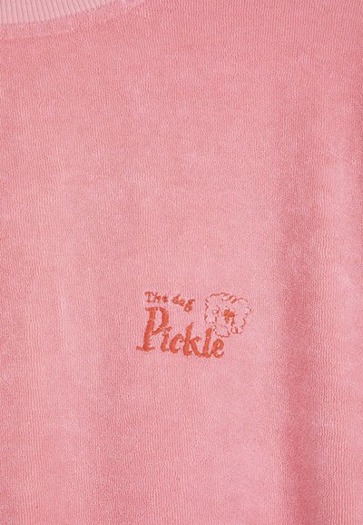 Tissu rose texturé avec un texte brodé « The dry Pickle » et un petit visage d'animal en style cartoon en fil orange.