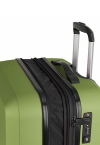 Valigia rigida verde con finitura testurizzata, zip nera, doppie zip e lucchetto a combinazione. Manico retrattile in tono argento.