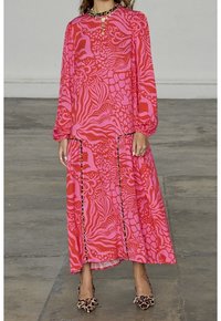 Robe rose à manches longues présentant des motifs abstraits audacieux dans différentes nuances de rose. Design fluide avec un ourlet échelonné à la cheville.