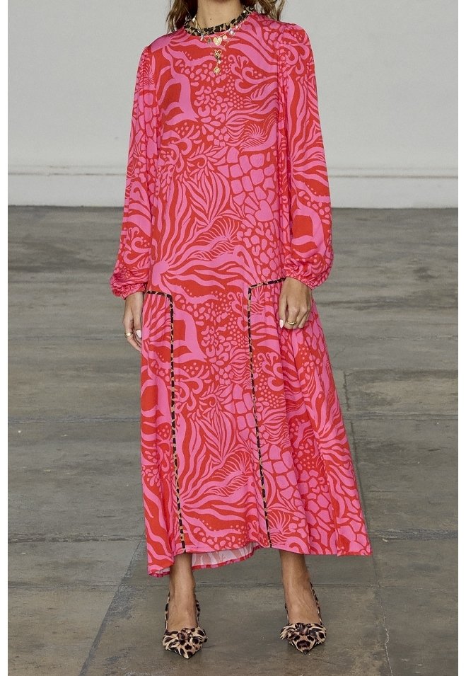 Robe rose à manches longues présentant des motifs abstraits audacieux dans différentes nuances de rose. Design fluide avec un ourlet échelonné à la cheville.