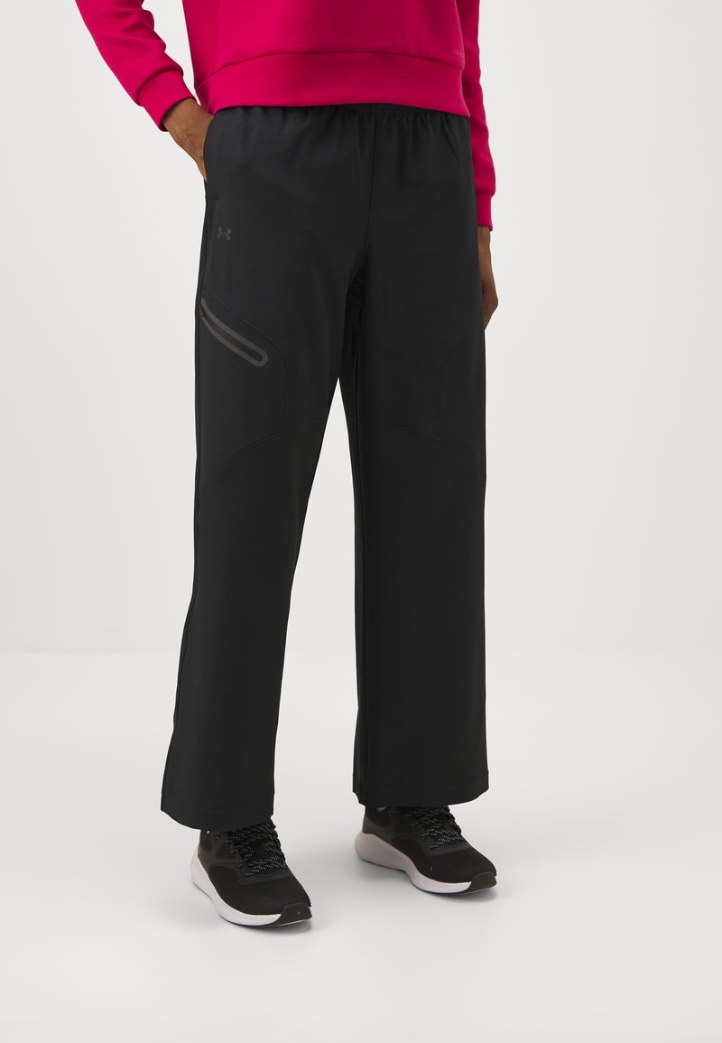 Mustat urheiluhousut, joissa on rento istuvuus, hienovarainen vetoketjupussi ja sileä pinta, yhdistettynä mustiin urheilukenkiin.