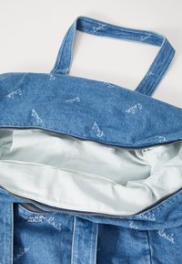 Τσάντα tote από τζιν με ανοιχτό μπλε εσωτερικό, φερμουάρ κλεισίματος και δύο λαβές. Διαθέτει διακριτικό λογότυπο στο εξωτερικό ύφασμα.