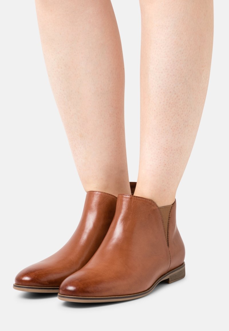 Botas de tobillo de cuero marrón con un acabado suave, paneles laterales elásticos, punteras redondeadas y un tacón bajo apilado.