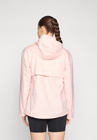 Light pink waterproof jacket with a hood, featuring a back vent and elastic cuffs. Smooth texture and ventilated design for breathability.