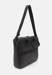 Borsa a tracolla in pelle nera con tracolla rimovibile, dotata di due manici superiori e una texture liscia e raffinata. Chiusura con zip e design minimalista.