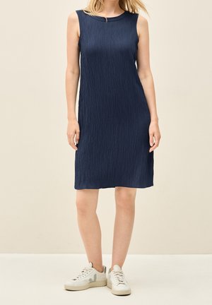 Sleeveless navy blue knee-length dress with textured fabric worn with white sneakers on a neutral background.