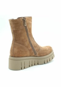 Bruine suède enkellaars met een zijrits, chunky beige zool en gestructureerde details op de bovenkant, voorzien van een ronde neus.