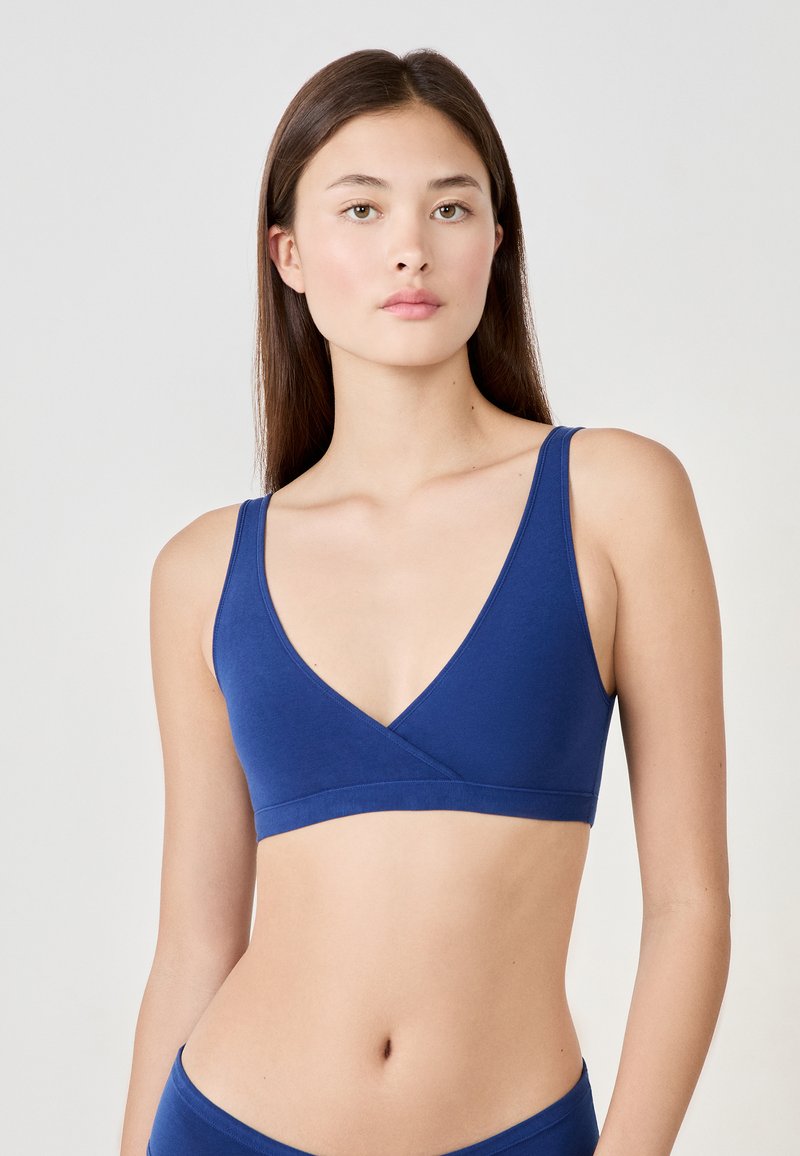 Navy blauwe bralette van zachte stof, met een v-halsontwerp, brede banden en een naadloze afwerking. Minimalistische en comfortabele stijl.