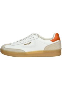 Bílé tenisky s akcenty z béžové nubukové kůže, oranžovým patním tabem a perforovanými boky. Mají šněrovací design a gumovou podrážku. Značka je zobrazena.