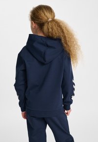 Felpa con cappuccio blu navy realizzata in tessuto morbido, dotata di tasca a marsupio, polsini a coste e tre strisce orizzontali sulla manica.