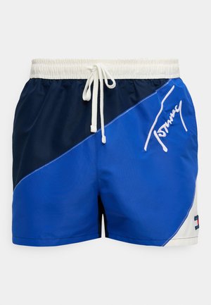 Blå svømmebukser laget av lett stoff med hvit snøring i livet. Har et fargedelt design i marineblått og lyseblått med logodetalj.
