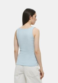 Canotta azzurro chiaro con un design aderente e texture a coste, caratterizzata da un collo rotondo e senza maniche. Stile semplice e minimalista.