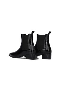 Zwarte chelsea boots met een glanzende afwerking, elastische zijkanten en een lage blokhak. Voorzien van aantreklussen voor gemakkelijk aan- en uittrekken.