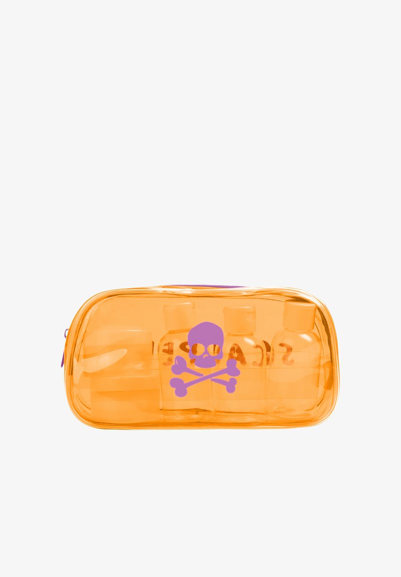 Borsa cosmetica trasparente arancione con una grafica di teschio e ossa incrociate viola. Contiene tre piccoli flaconi visibili all'interno. Chiusura con cerniera.