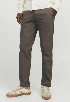 Brown cotton chinos with a straight fit, featuring side pockets. Paired with beige and light brown sneakers.