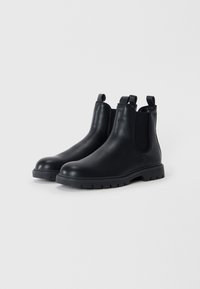 Zwarte leren Chelsea boots met elastische zijpanelen, trektabs en robuuste rubberen zolen. Slanke silhouet met een gladde textuur.
