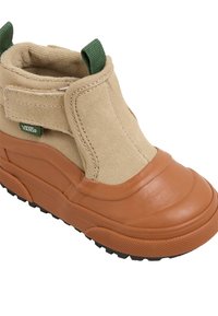 Botín de ante color tan con punta de goma marrón, suela texturizada y tirador verde. Cuenta con una correa de velcro para facilitar su uso.