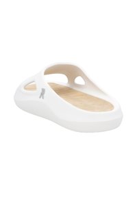 Sandale blanche à glissière avec des côtés découpés, une texture extérieure lisse et un semelle intérieure marron clair. Présente un petit logo gris près de la zone du talon.