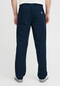 Navy blauwe, elastische broek met twee achterzakken en een gladde textuur. Eenvoudig ontwerp, geschikt voor casual gebruik.