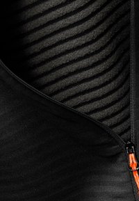 Black zippered garment showing a textured black interior with horizontal lines. Features an orange zipper pull and smooth exterior finish.