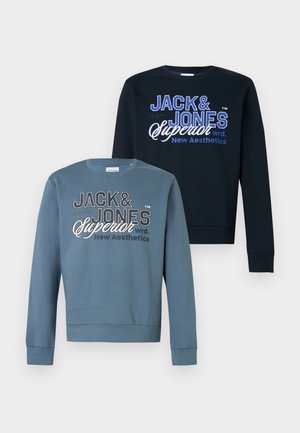 Dwie bluzy Jack & Jones z długim rękawem, jedna w ciemnoniebieskim, a druga w stonowanym niebieskim kolorze, obie z białym i niebieskim logo na piersi.