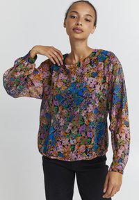 Blusa floreale in tessuto trasparente, caratterizzata da un motivo multicolore con tonalità di rosa, blu e verde. Vestibilità ampia e maniche arricciate.
