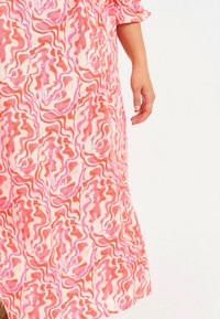 Rosa und pfirsichfarbene Kleid mit einem wellenförmigen abstrakten Muster, aus leichtem Stoff gefertigt, mit lockerer Passform und gerafften Ärmeln.