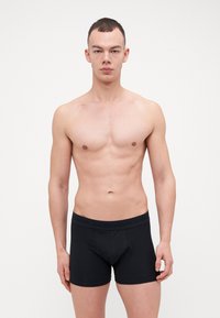 Sorte boxer short i mykt materiale, med en tettsittende design, elastisk linning med preget logo og glatt tekstur.