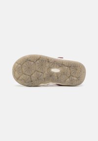 Sandal outsole with a textured rubber surface, featuring a star-pattern design and speckled accents in beige and pink hues.