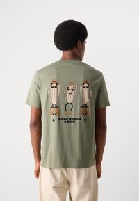 Olijfgroen T-shirt met een speelse graphic van drie antropomorfe cactussen in cowboyhoeden en laarzen, met daaronder de tekst "MARC O'POLO DENIM".