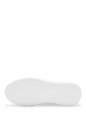 Sålen på en hvid sneaker med en tekstureret, skridsikker overflade og en let forhøjet hæl, vist mod en hvid baggrund.